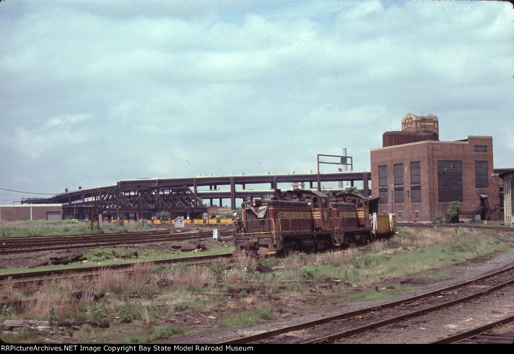 BM 1230 & BM 802 haul welded rail for the MBTA Green Line 'D' Branch past Boston Engine Terminal